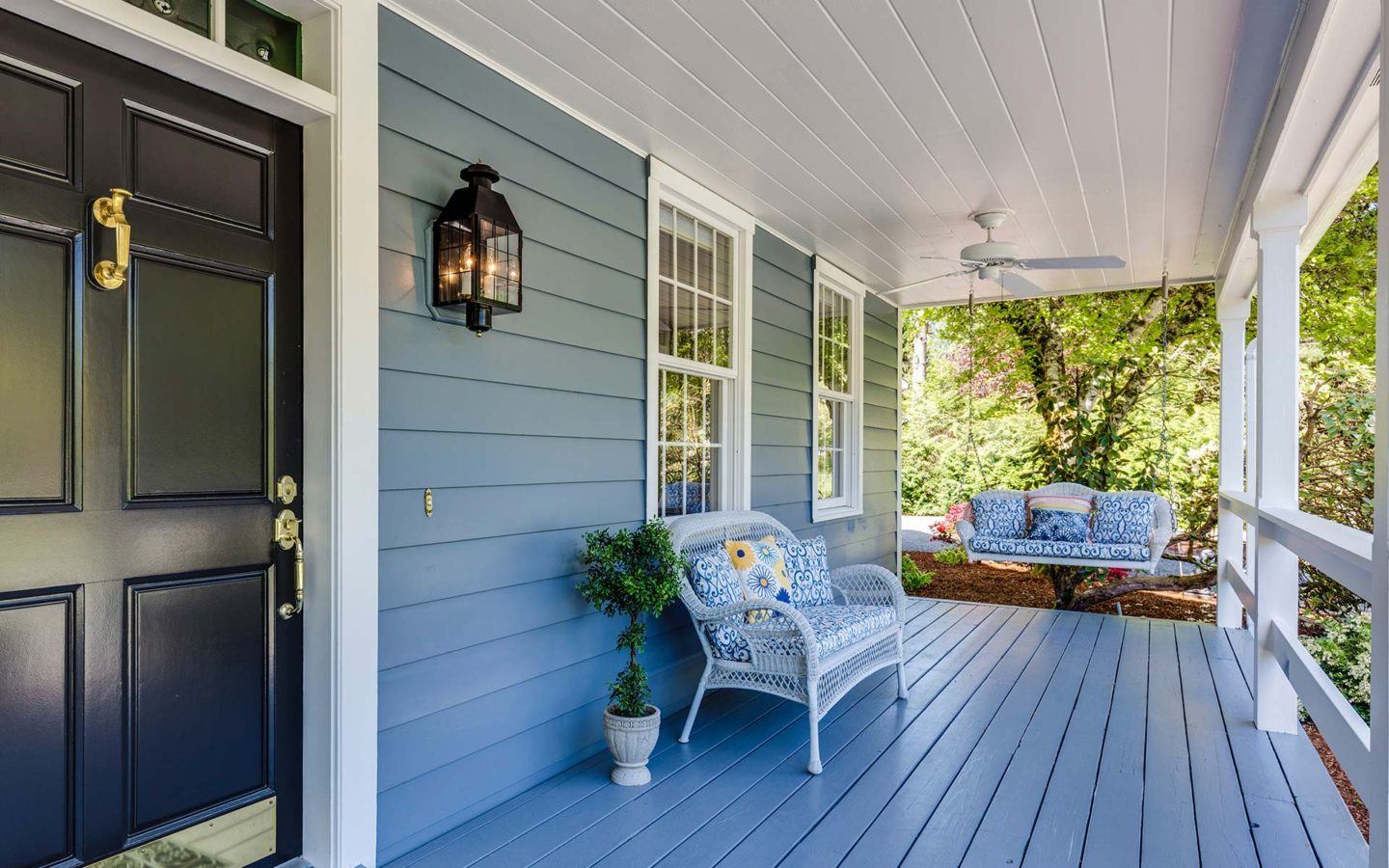 blue painted front porch and home with blue siding a porch swing and arm chair